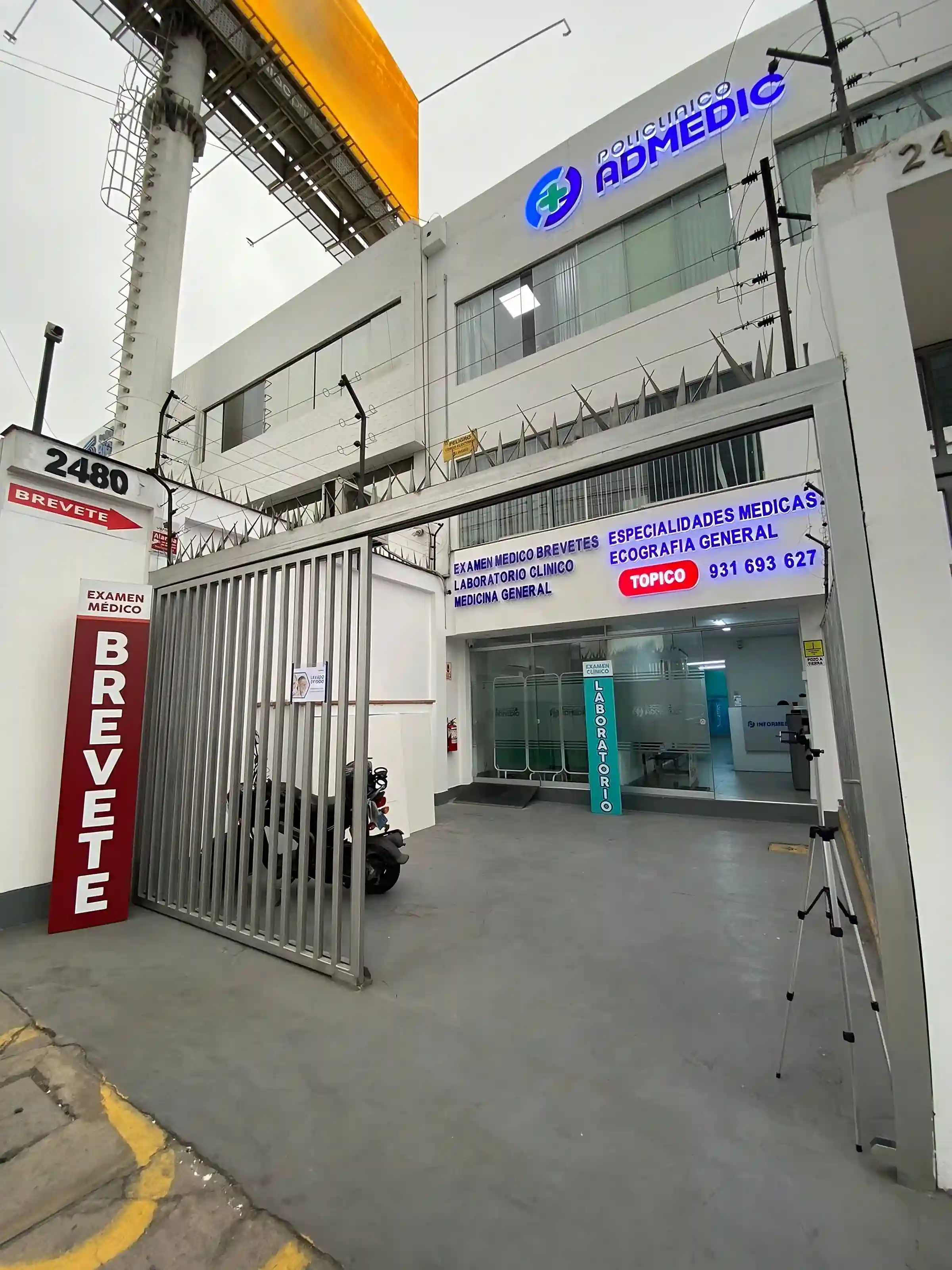 Fachada exterior e ingreso principal del Policlínico Admedic con lista de especialidades médicas.
